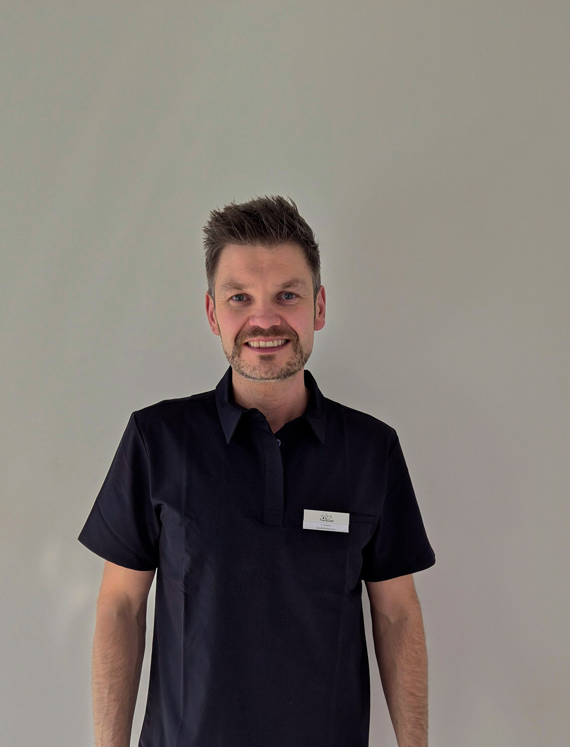 Person in blauer Arbeitskleidung steht.