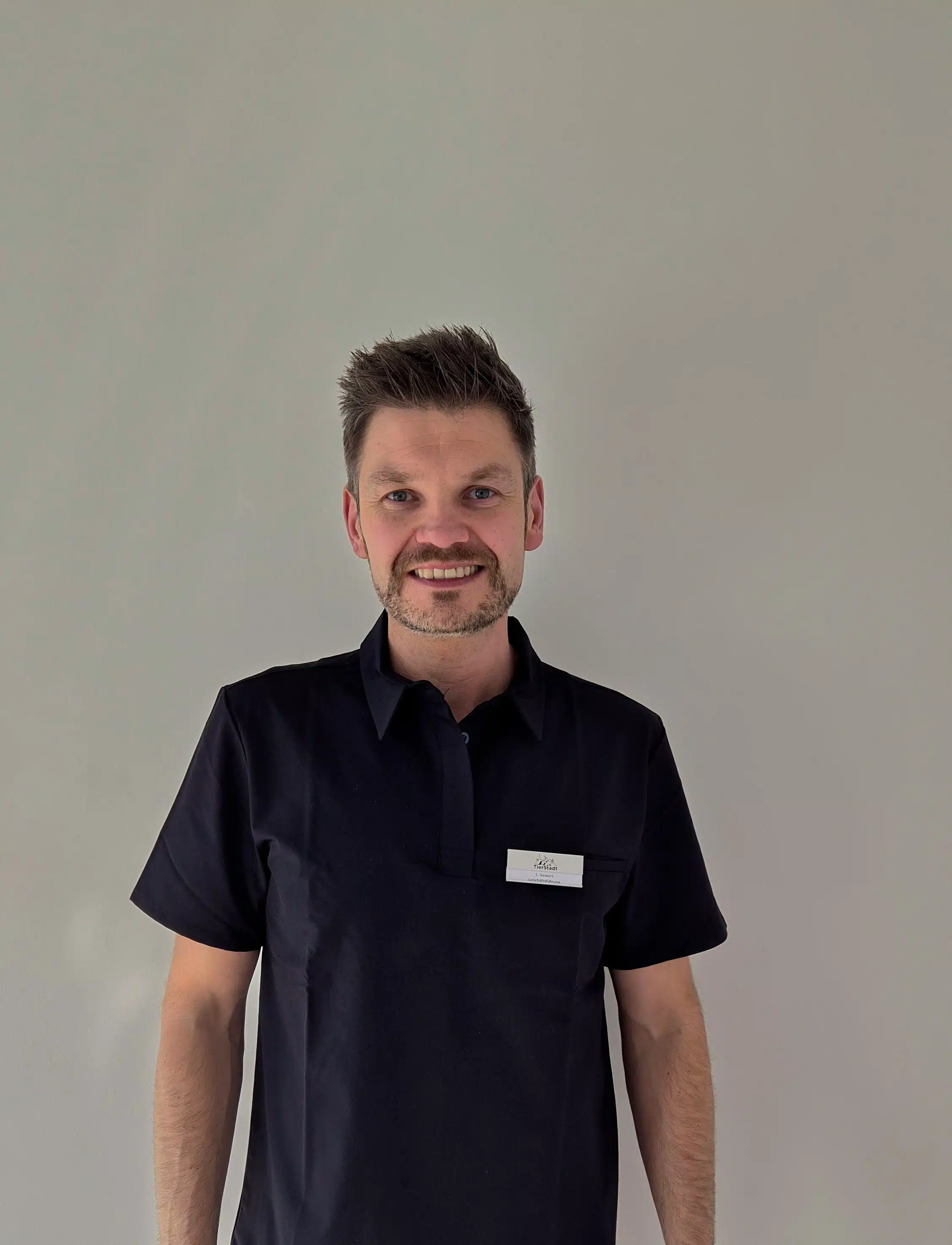Person in blauer Arbeitskleidung steht.